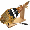 Cured serrano ham with a label on a wooden stand with a knife, on a white background
